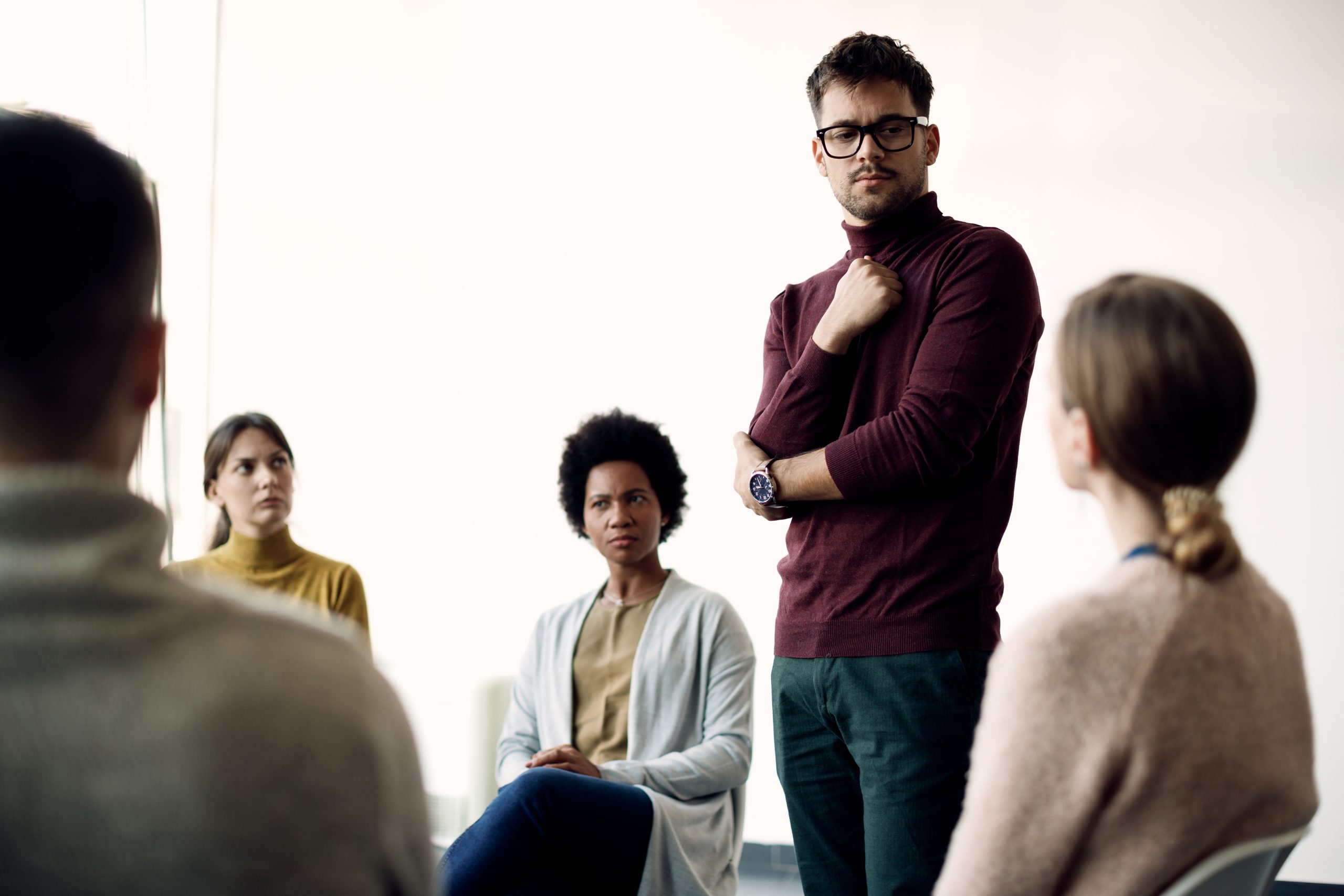 Young man communicating with support group during therapy at com